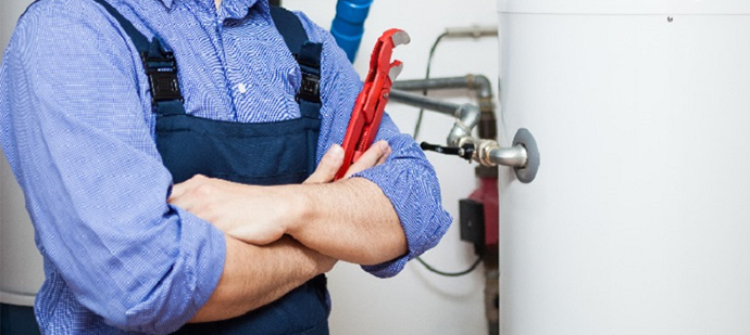 Cropped photo of a plumber standing beside a water heater