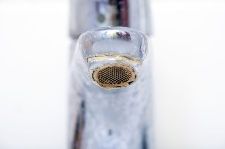 Close-up of a faucet’s aerator that is covered with limescale