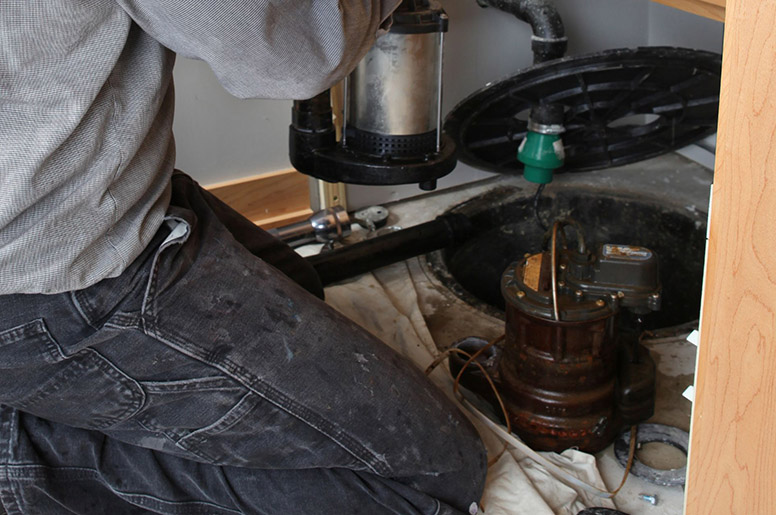 A plumber installing a sump pump in a basement 