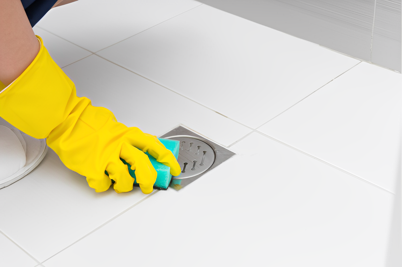  A person wearing a glove cleaning a drain with a blue sponge 