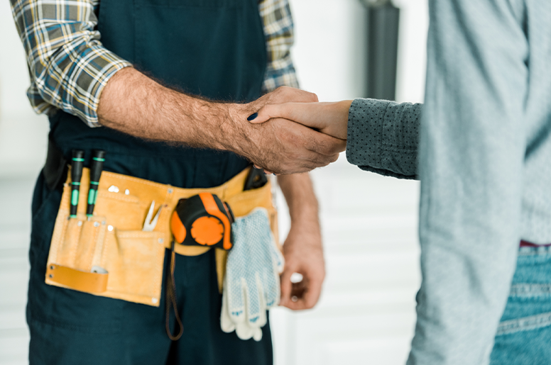 A plumber shaking hands with a client after successfully dealing with flood in a basement 