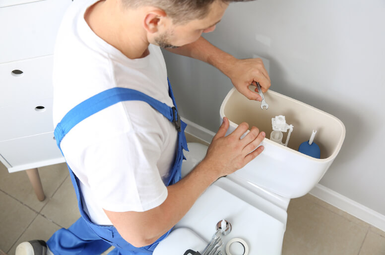 A plumber repairing a toilet 