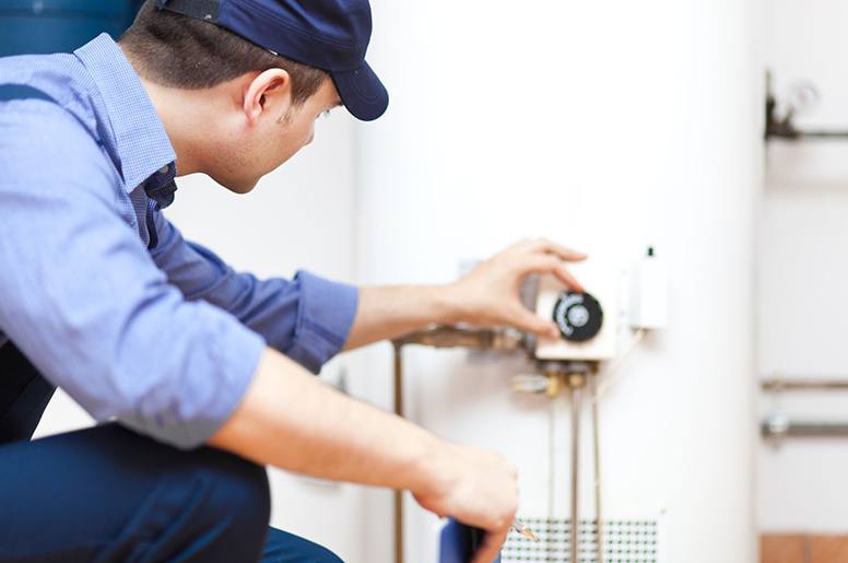 A plumber fixing a water heater tank