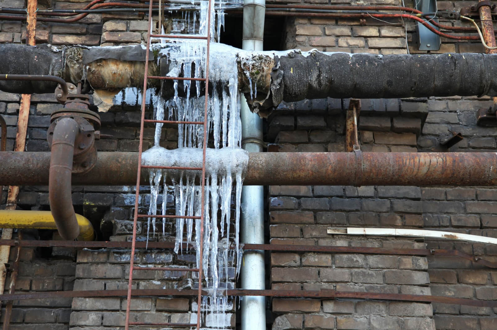 A row of rusty pipelines covered with ice from the cold air