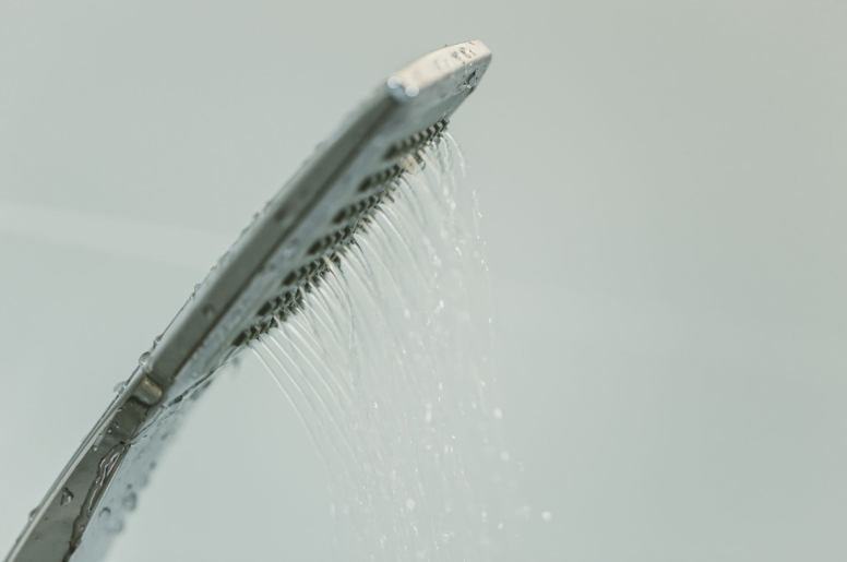 A stainless steel shower head spraying water at a low pressure 