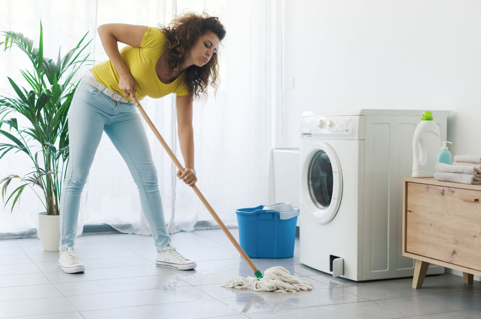 A woman mopping up water after a washing machine leak