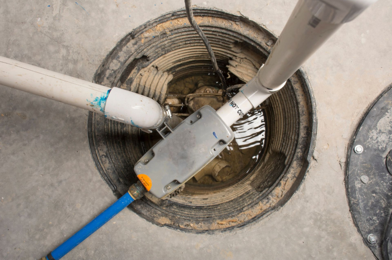 An opened sump pump with pipes and vacuums placed inside